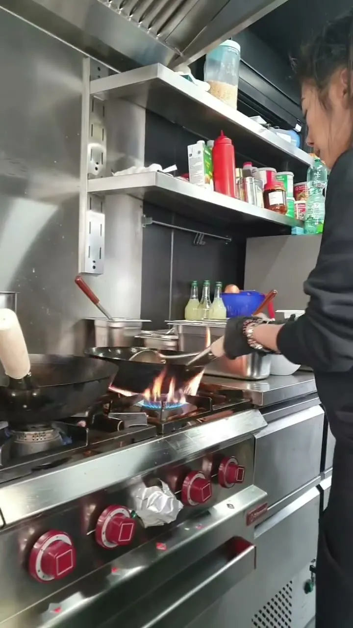 Koch am Gasherd mit mehreren Woks